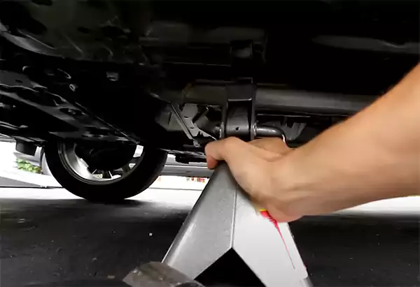Placing a jack stand under a jacked up car